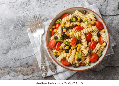 Fresh homemade colorful vegan fusilli pasta salad with beans, corn, tomato and jalapeno close-up in a plate on the table. Horizontal top view from above
 - Powered by Shutterstock