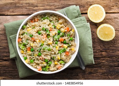 Fresh Homemade Cooked White Quinoa With Colorful Vegetables (green Peas, Sweet Corn Kernels, Green Beans, Carrots) And Parsley In Bowl, Lemon On The Side, Photographed Overhead