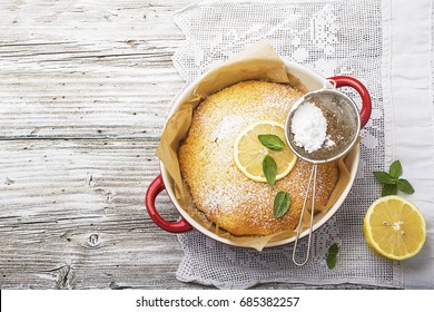 Fresh homemade cream cheese sweet cake for breakfast with slices of lemon and thyme on olive board on a simple light wooden background. Top view