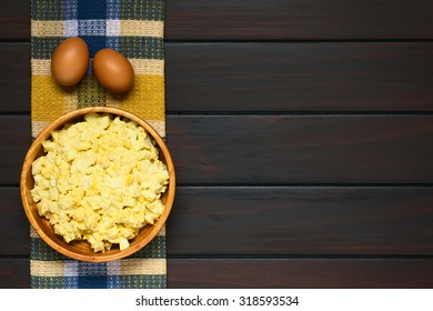 Fresh Homemade Egg Salad Prepared With Mayonnaise And Mustard In Wooden Bowl, Raw Eggs Above, Photographed Overhead On Dark Wood With Natural Light