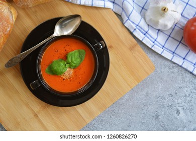 Fresh Homemade Italian Tomato Soup With Basil And A Dollop Of Sour Cream In A Soup Pot With An Italian Bread Roll And A Tomato On A Stone Surface