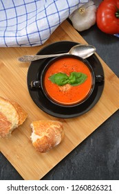 Fresh Homemade Italian Tomato Soup With Basil And A Dollop Of Sour Cream In A Soup Pot With An Italian Bread Roll And A Tomato On A Stone Surface