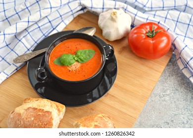 Fresh Homemade Italian Tomato Soup With Basil And A Dollop Of Sour Cream In A Soup Pot With An Italian Bread Roll And A Tomato On A Stone Surface