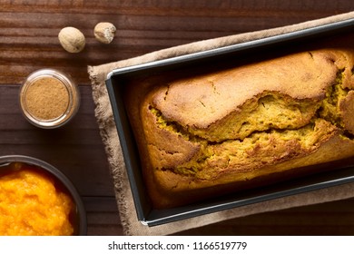 Fresh Homemade Pumpkin Bread In Pan, Ingredients (pumpkin Puree, Cinnamon, Nutmeg) On The Side, Photographed Overhead (Selective Focus, Focus On The Top Of The Bread)