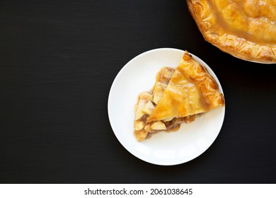 Fresh Homemade Salted Caramel Apple Pie On A White Plate On A Black Surface, Top View. Flat Lay, Overhead, From Above. Copy Space.