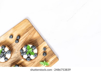 Fresh homemade tart with cream, blueberries and basil leaves on white stone background with copy space for your design. Food blog or cook book cover concept. - Powered by Shutterstock