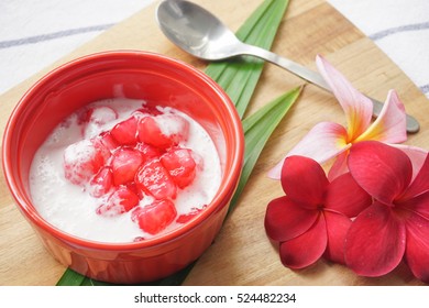 Fresh Homemade Thai Red Rubies Dessert (Tub Tim Krob) - Red Water Chestnuts In Syrup Served With Coconut Milk In A Bowl On Small Wooden Serving Boards