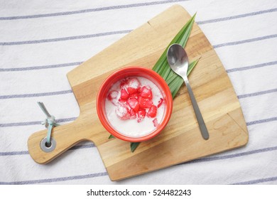 Fresh Homemade Thai Red Rubies Dessert (Tub Tim Krob) - Red Water Chestnuts In Syrup Served With Coconut Milk In A Bowl On Small Wooden Serving Boards