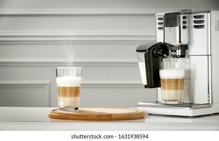 Fresh Hot Caffe Latte In Glass And White Coffee Machine On Board.Free Space For Your Decoration And White Wall In Home Interior. 