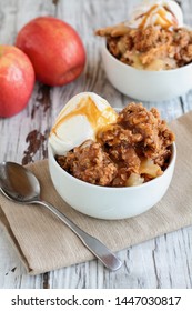 Fresh Hot Homemade Apple Crisp Or Crumble With Crunchy Streusel Topping Topped With Vanilla Bean Ice Cream And Caramel Sauce. Selective Focus With Blurred Background. 