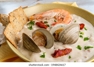 Fresh hot New England clam chowder soup with whole shrimp crackers and parsley garnish - Shutterstock ID 1948424617
