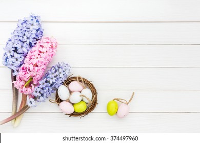 Fresh hyacinths and decorative Easter eggs in small nest on white table. Top view, copy space 
