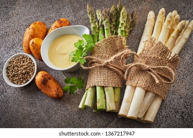 Fresh ingredients for asparagus starter with new baby potatoes, peppercorns, mayonnaise, coriander and two bundles of white and green asparagus spears viewed top down