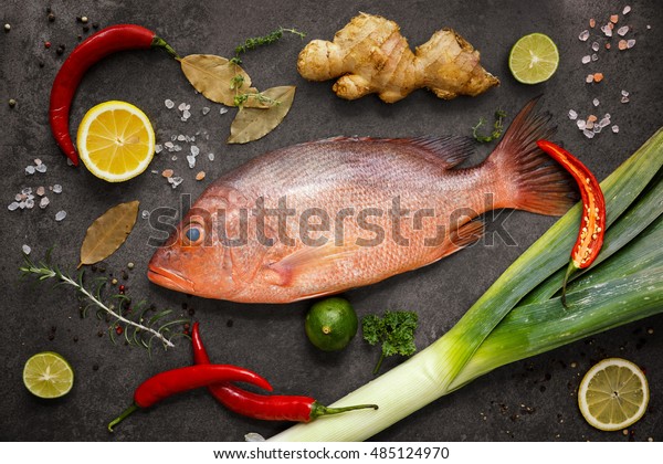 Fresh ingredients to cook\
fish, red snapper, leak, lime, lemon, parsley, chili pepper,\
ginger. Top view