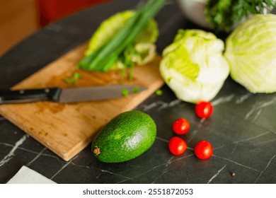 Fresh ingredients, including avocado, lettuce, cherry tomatoes, and green herbs, neatly arranged on a wooden cutting board with a kitchen knife.
A composition of vegetables on a dark marble countertop - Powered by Shutterstock