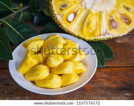 Fresh Jackfruit in white dish, half of jack fruit and jackfruit leaf on wooden table.