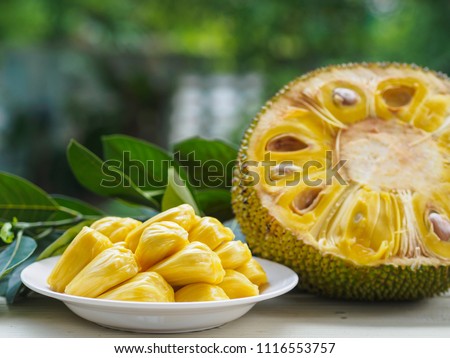 Fresh Jackfruit in white dish, half of jack fruit and jackfruit leaf on wooden table.