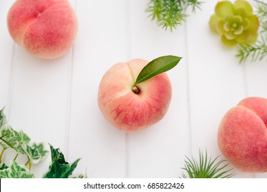 Fresh Japan White Peaches and Green Leaves on Wooden White Background 