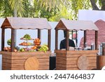 Fresh juice bar with a range of tropical fruit including oranges, apples bananas and pineapples on wood background in front of blue sky and Palm trees, outdoor shop with fresh fruits juices in Qatar.