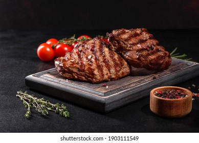 Fresh Juicy Delicious Beef Steak On A Dark Background. Meat Dish With Spices And Herbs