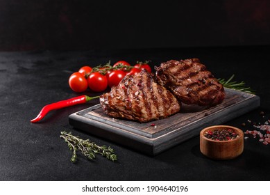 Fresh Juicy Delicious Beef Steak On A Dark Background. Meat Dish With Spices And Herbs