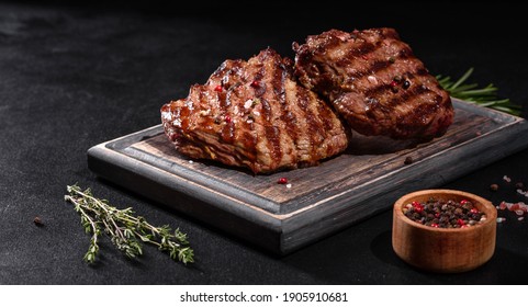 Fresh Juicy Delicious Beef Steak On A Dark Background. Meat Dish With Spices And Herbs