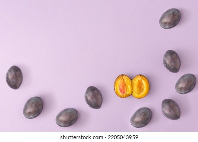 Las ciruelas jugosas y frescas se esparcen sobre un fondo púrpura pastel. Concepto creativo de fruta sana. Foto de stock