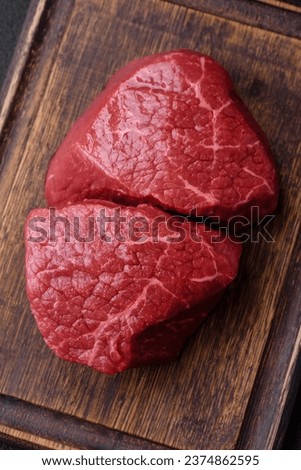 Fresh juicy raw beef medallions with salt and spices on a dark concrete background
