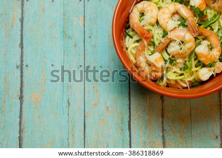 Fresh jumbo shrimp bedded on spiralized zucchini on a wood plank board