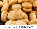 Fresh Kaiser rolls stacked on a store shelf. Group of classic bread rolls on display. Bakery section with a pile of golden brown buns. Perfect for sandwiches or breakfast. Crisp, freshly baked roll.