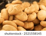 Fresh Kaiser rolls stacked on a store shelf. Group of classic bread rolls on display. Bakery section with a pile of golden brown buns. Perfect for sandwiches or breakfast. Crisp, freshly baked roll.