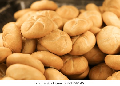 Fresh Kaiser rolls stacked on a store shelf. Group of classic bread rolls on display. Bakery section with a pile of golden brown buns. Perfect for sandwiches or breakfast. Crisp, freshly baked roll.