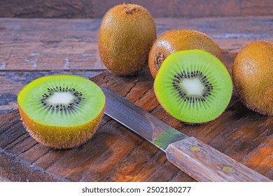 Fresh kiwifruit cut in half on a wooden cutting board. - Powered by Shutterstock