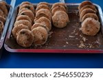 Fresh kue piah filled with sweet mashed mung beans, served on a red plastic tray, sold by a traditional street vendor. Kue piah is a type of pastry that is popular in Southeast Asia