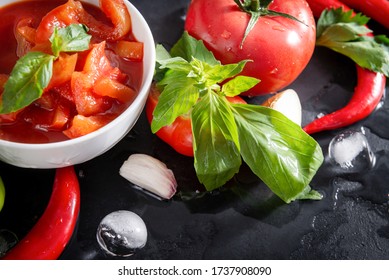 fresh Lecho  with a sprig of green Basil, tomato slices,  ice cubes,  red chili pepper, garlic on a black background, sauce top view, - Powered by Shutterstock