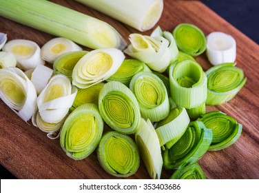 Fresh leeks whole and sliced on a wooden kitchen board