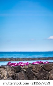 Fresh Lei Flowers Necklace On Shore Beach, Kauai Hawaiian Island Tropical Vacation Background. Hawaii Luau Icon Travel Concept. Selective Focus.