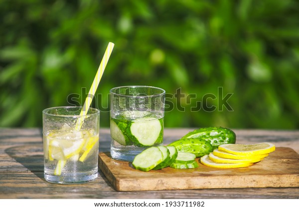 fresh lemon and cucumber lemonade.\
drinking straw in glass. chopped fruit slices in\
water