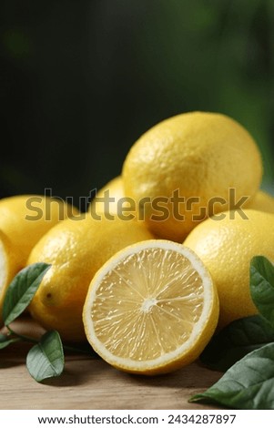 Fresh lemons and green leaves on wooden table, closeup