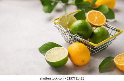 Fresh lemons and limes with leaves in a supermarket basket on a light textured background close up. Citrus fruit concept for freshly squeezed lemonade. Macro view and copy space.