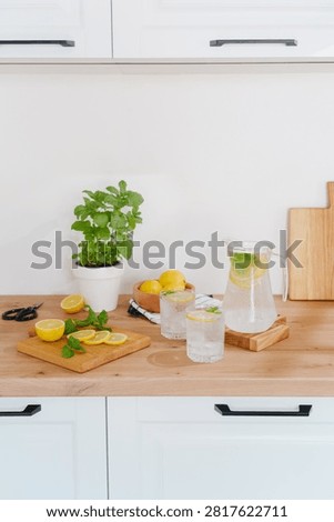 Fresh lemons, mint, and cold drinks on a kitchen counter.