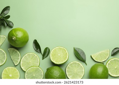 Limas y hojas frescas sobre fondo verde pálido, capa plana. Espacio para texto