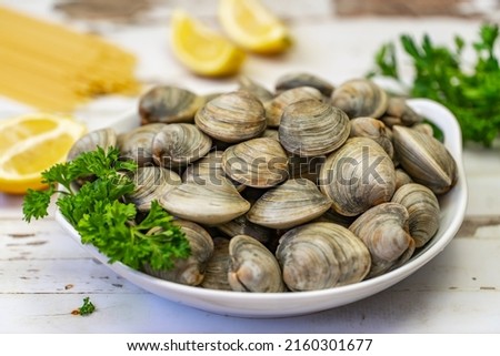 Fresh Littleneck Clams on a white plate with parsley.