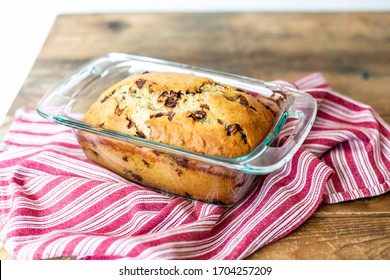 Fresh Loaf of Banana Chocolate Chip Bread in Glass Baking Pan on Farmhouse Table with Red Ticking Fabric Dishcloth