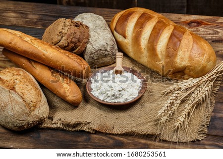 Fresh loaves of bread with wheat and gluten on a wooden table