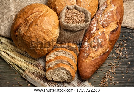 Fresh loaves of bread with wheat and gluten on a wooden table
