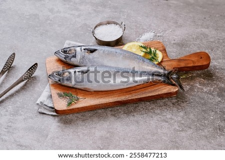 Fresh mackerel is elegantly presented on plates and cutting boards, with garnishes like rosemary and lemon slices. The setup highlights their natural freshness, ready for preparation   