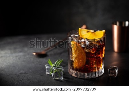 Fresh made Cuba Libre cocktail with brown rum, cola and lemon on wooden background