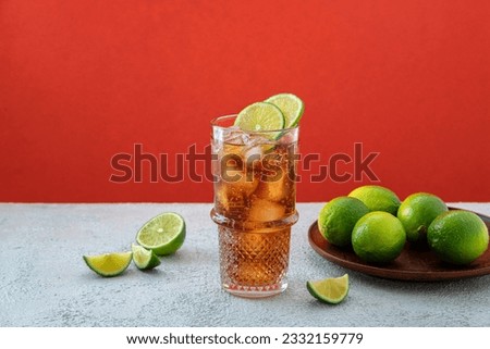 Fresh made Cuba Libre with rum, cola and lime on color background. Cold longdrink