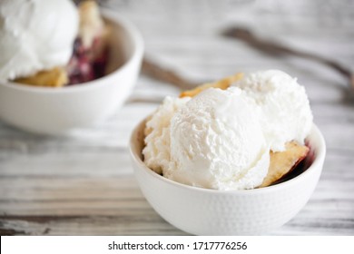 Fresh made homemade cherry cobbler served with two scoops of vanilla ice cream. Selective focus with blurred background.